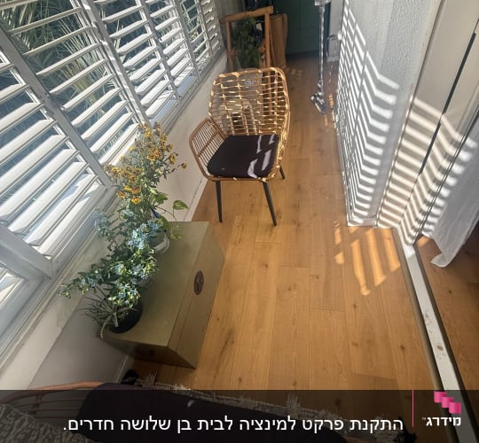 רצפת פרקט עם כיסא ופרחים ליד חלון